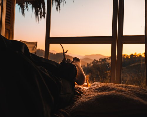 Person enjoying a book by a softly lit window during the evening